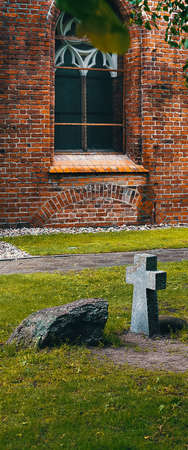 An ancient tombstone with a stone cross is unknown to anyone near the brick wall of the castle.の写真素材