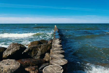 Large stones lie on the beach in front of the waves.の写真素材