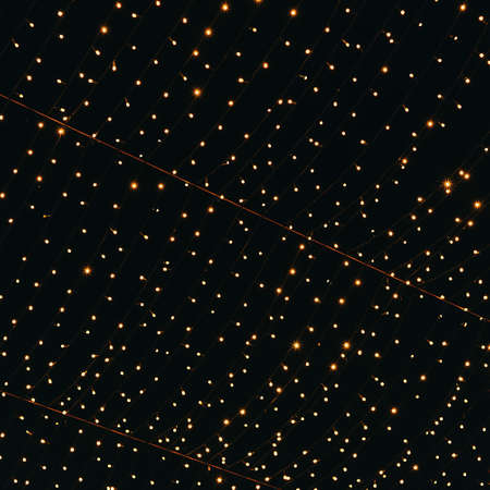 Many lightbulbs hanging on cable as garland decorative isolated on dark night sky background