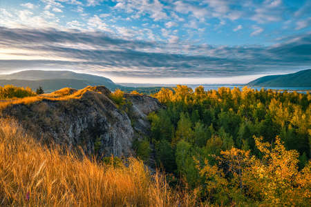 Beautiful landscape with mountains and hills, river and forest with cloudy sky.の写真素材