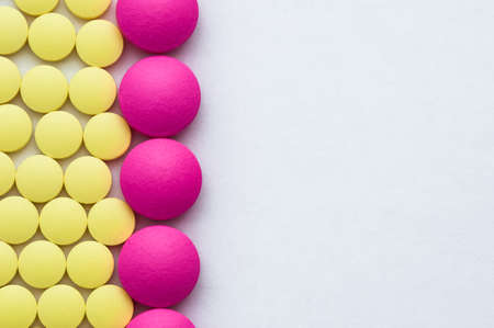 Pink and yellow pills in a row on a white background.の写真素材
