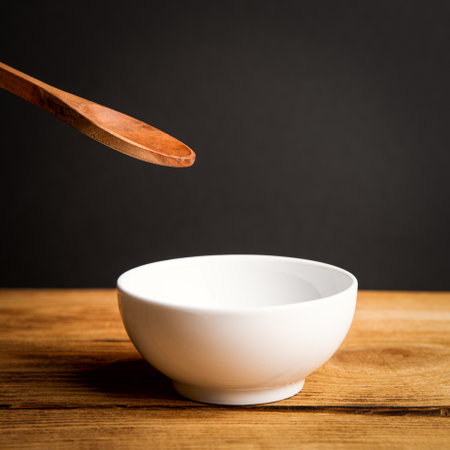 A white ceramic cup, a wooden spoon above it on a wooden table.の写真素材