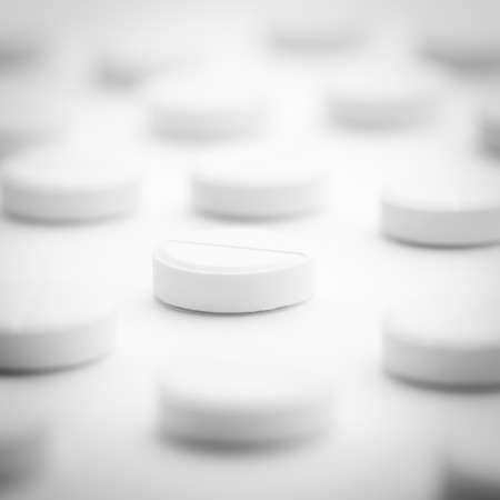 A pile of white pills scattered on a bright white background. Selective focus.の写真素材