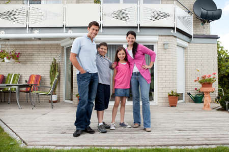 Caucasian mother and father with children standing in front of houseの写真素材