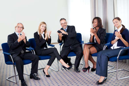 Portrait of a team of happy successful businesspeople sitting together smiling and celebrating at...