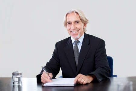 Portrait of a happy mature male entrepreneur working at the officeの写真素材