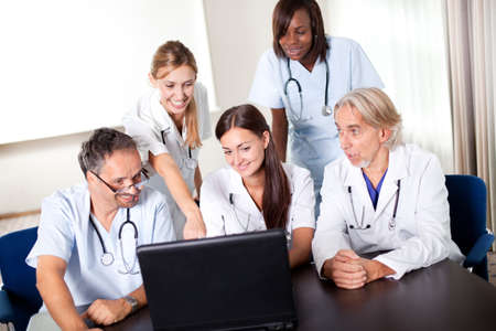 Portrait of group of smiling hospital colleagues looking at the laptop and discussingの写真素材