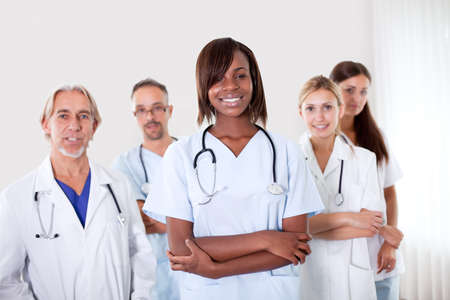 Close-up portrait of pretty young female doctor with colleagues in the backgroundの写真素材