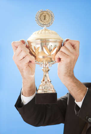 Portrait of senior businessmen holding a trophy on skyの写真素材