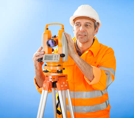 Portrait of Senior land surveyor working with theodolite at construction siteの写真素材