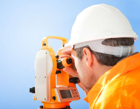 Portrait of Senior land surveyor working with theodolite at construction siteの写真素材