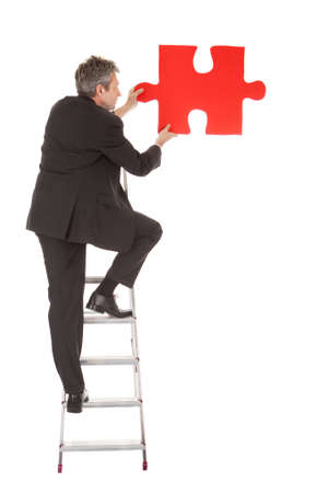 Senior businessman holding a jigsaw puzzle. Isolated in whiteの写真素材
