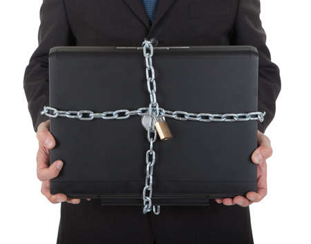 Businessman holding laptop with chain and lock. Isolated on white