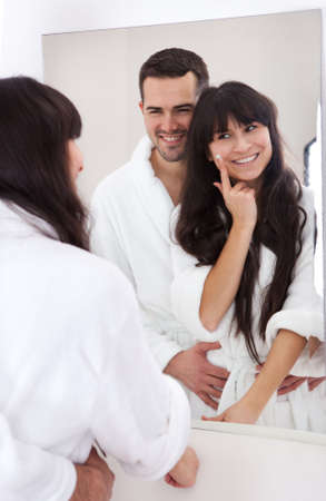 Playful young couple applying cream in the bathroomの写真素材