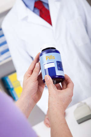 Close-up on hand holding a pill container at drug storeの写真素材