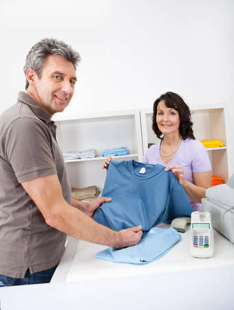 Senior adult men purchasing t-shirt at storeの写真素材