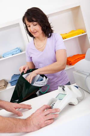 Assistant selling and packing t-shirts at storeの写真素材