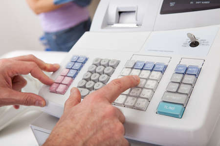 Sales person entering amount on cash register in retail storeの写真素材