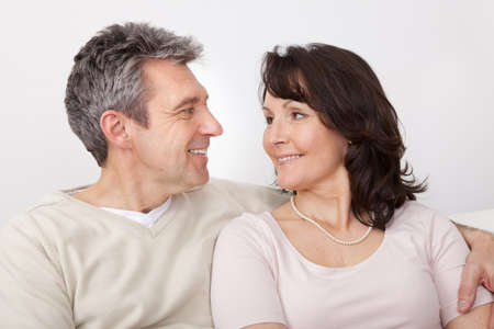 Portrait of happy mature couple sitting at home in the couchの写真素材