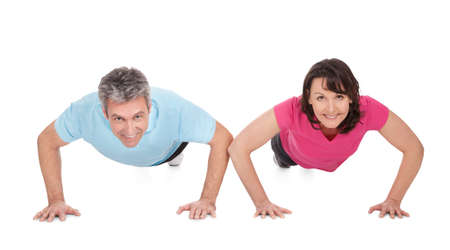 Active mature couple doing pushups. Isolated on white
