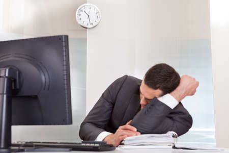 Successful businessman sleeping at desk it the officeの写真素材