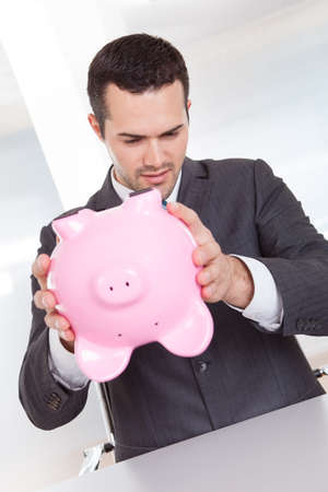Successful businessman holding piggybank at the officeの写真素材