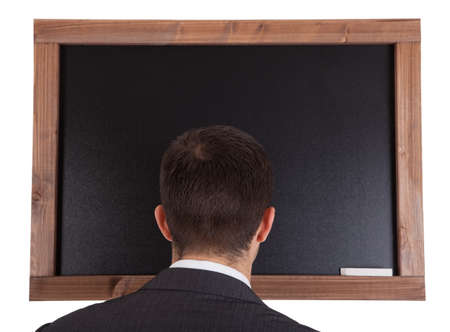 Businessman standing in front on blackboard. Isolated on whiteの写真素材