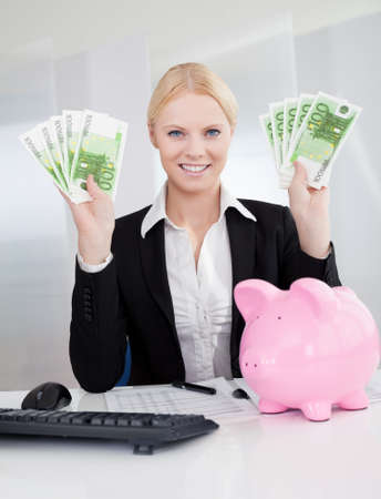 Businesswoman holding euro currency notes in the officeの写真素材