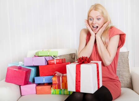 Beautiful young woman with her presents on the sofaの写真素材