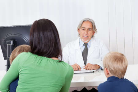 Mother and kids sitting at doctor officeの写真素材