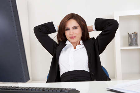 Portrait of a beautiful young businesswoman at desk relaxingの写真素材