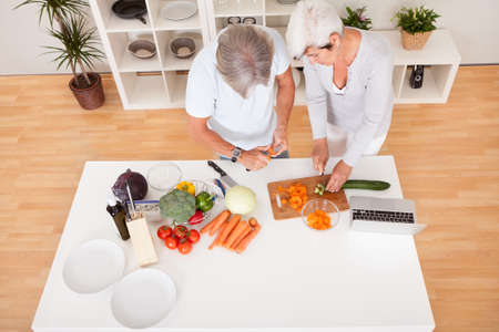 High angle view of an attractive middle-aged couple preparing a meal chopping vegetables in their kitchenの写真素材