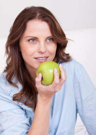 Young attractive woman eating a healthy juicy green appleの写真素材