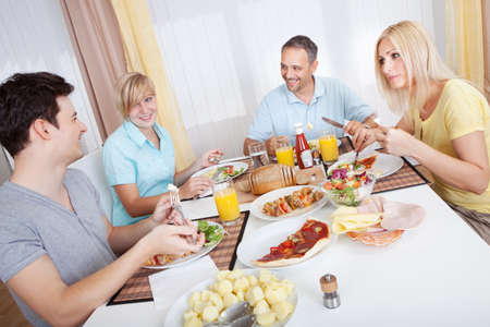Attractive family enjoying a healthy meal together seated around the tableの写真素材
