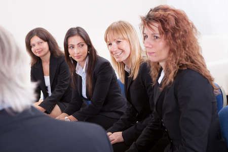 Businesswomen Looking At Mature Businessman In Meetingの写真素材