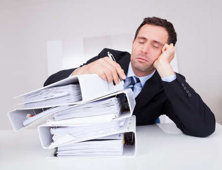 Bored Businessman Overwhelmed By Paperwork In The Office
