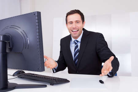 Portrait Of Happy Businessman Cheering At Workplaceの写真素材