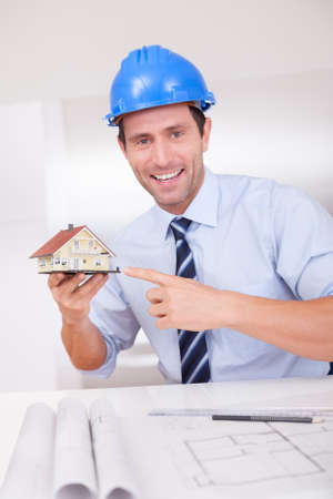 Portrait Of A Cheerful Architect Holding A House Modelの写真素材