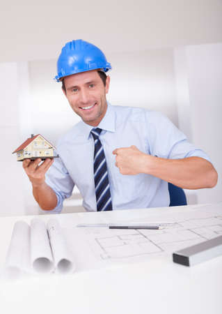 Portrait Of A Cheerful Architect Holding A House Model
