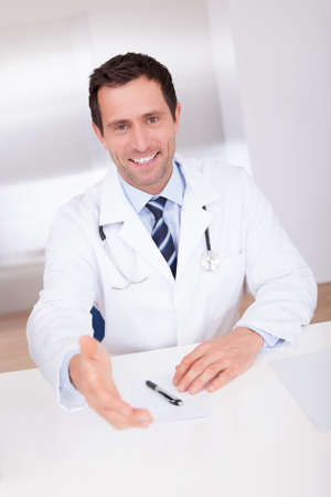 Portrait Of Happy Male Doctor Giving Hand For Handshakingの写真素材