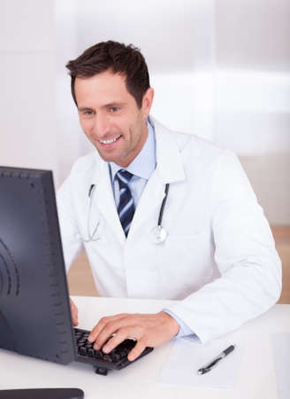 Smiling Medical Doctor With Stethoscope Sitting At A Deskの写真素材