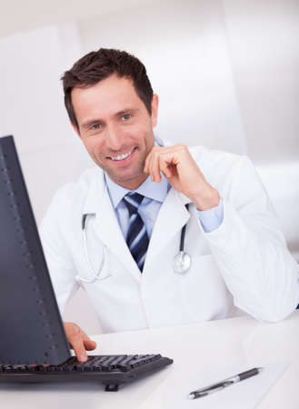 Smiling Medical Doctor With Stethoscope Sitting At A Deskの写真素材