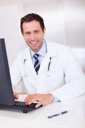 Smiling Medical Doctor With Stethoscope Sitting At A Deskの写真素材