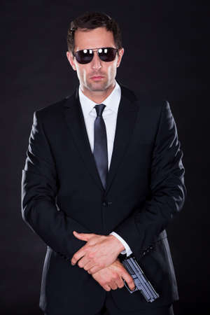 Portrait Of Young Man With Gun On Black Backgroundの写真素材