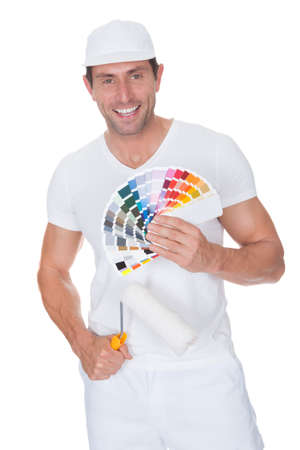 Painter Holding A Paint Roller And Spectrum Of Color Samples On White Backgroundの写真素材