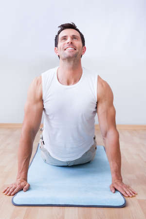 Young Man Exercising On Exercise Mat, Indoorsの写真素材