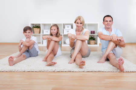 Family Doing Stretching Exercises Laying On The Carpet At Homeの写真素材