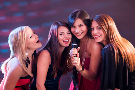 Four beautiful stylish girls singing karaoke at the club Four beautiful stylish girls singing karaoke at the club