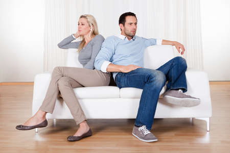 Couple who have fallen out over a disagreement sitting on a sofaの写真素材