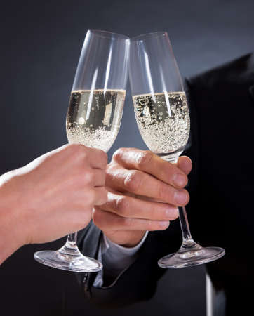 Romantic couple sitting having dinner in an elegant restaurant toasting each other with flutes of...